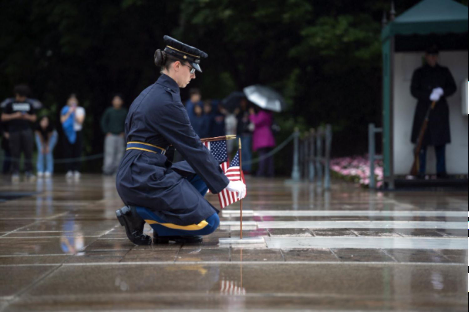 A soldier places a flag at a gravestone