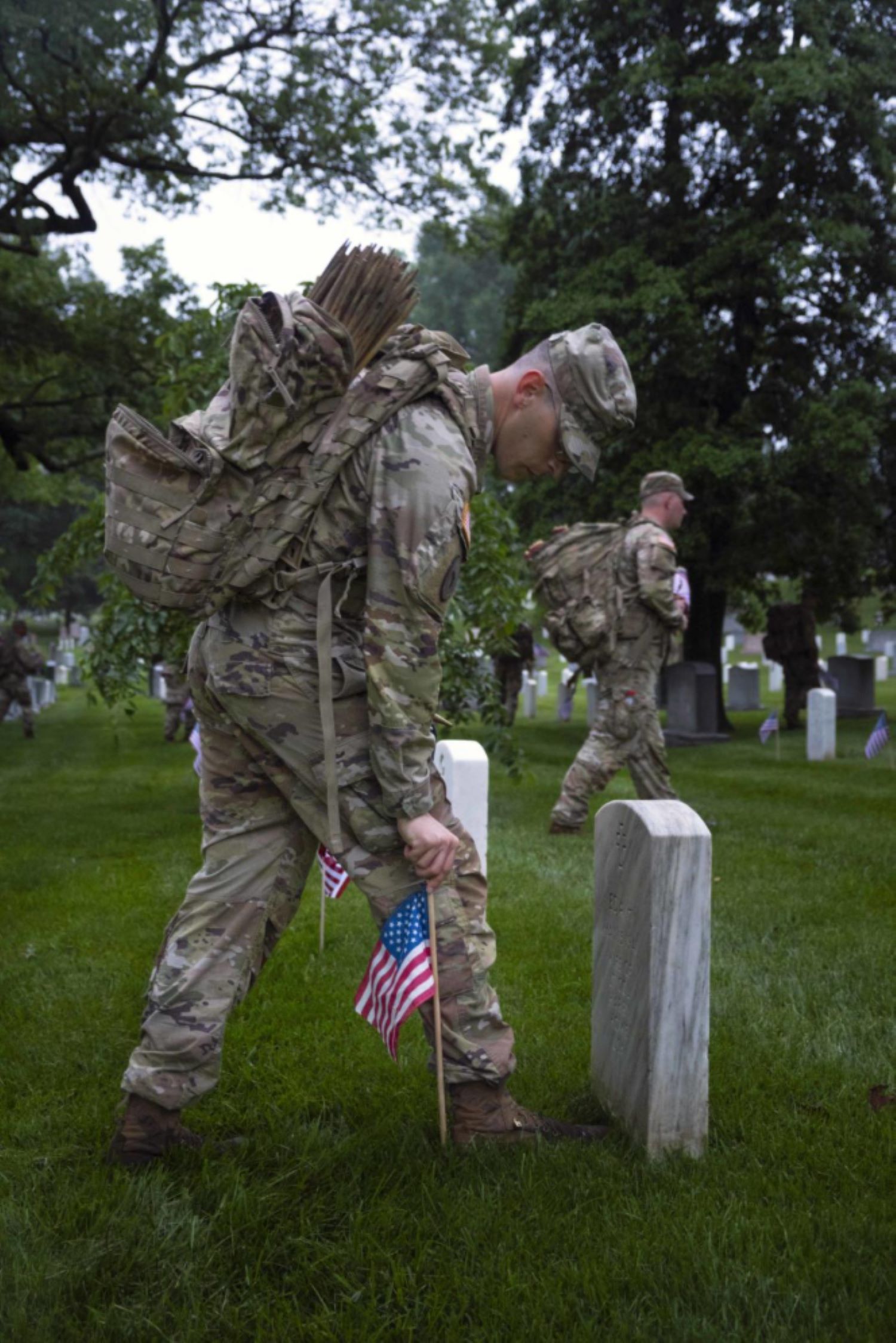Soldier places a flag at a gravestone
